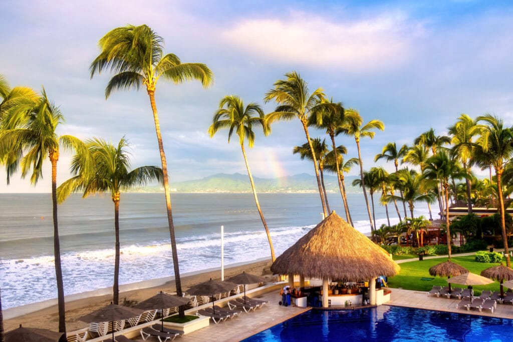 Hotel with palm trees and swimming pool on tropical beach romantic getaway