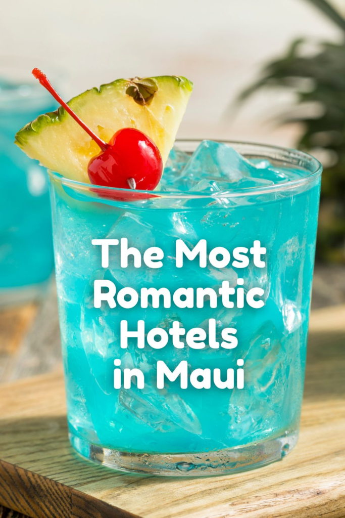 A vibrant blue cocktail garnished with a pineapple slice and cherry sits on a wooden surface. White text over the glass reads: Discover the most romantic hotels in Maui.