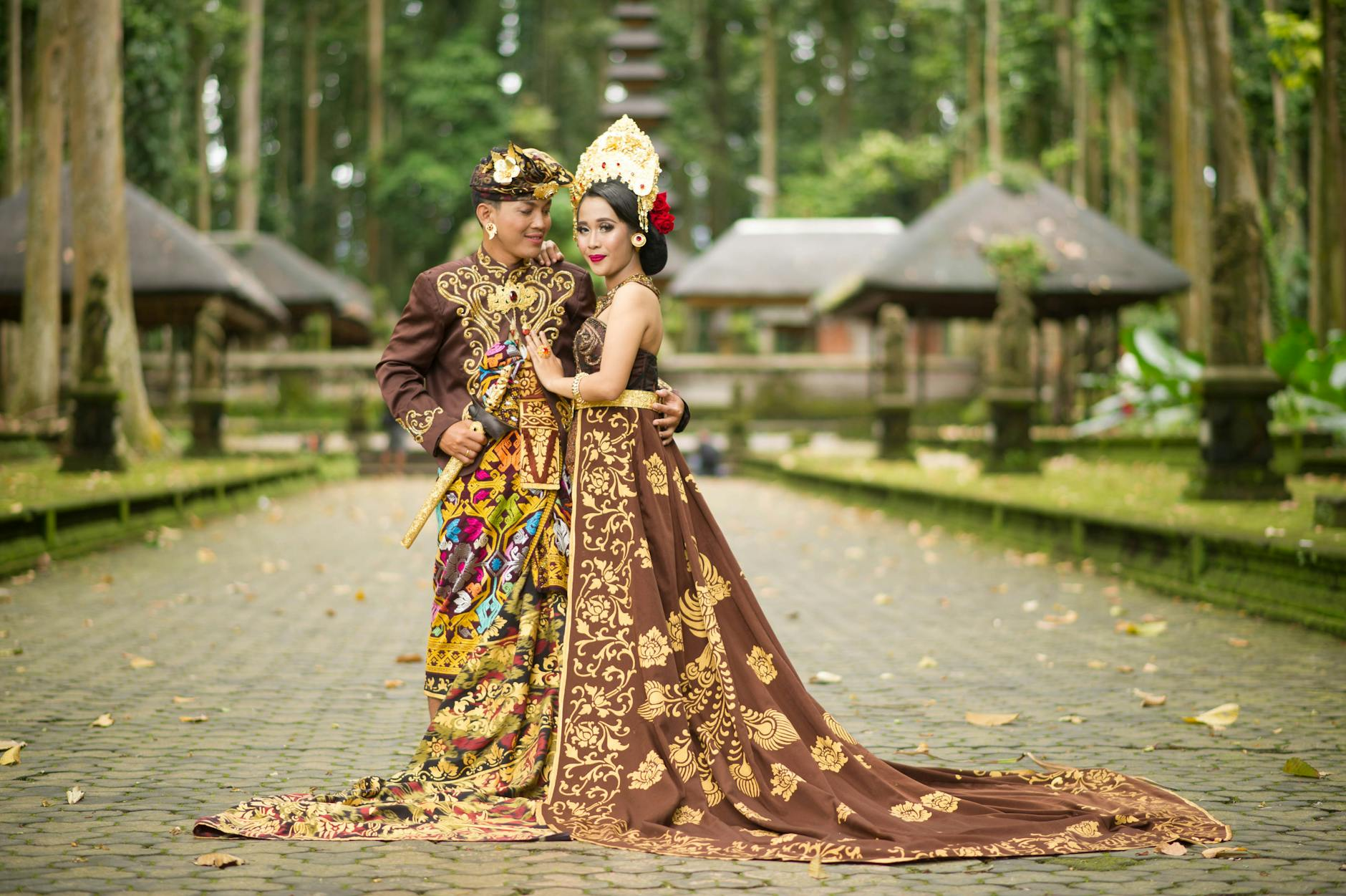 Couple in beautiful traditional Balinese attire posing outdoors for romantic honeymoon