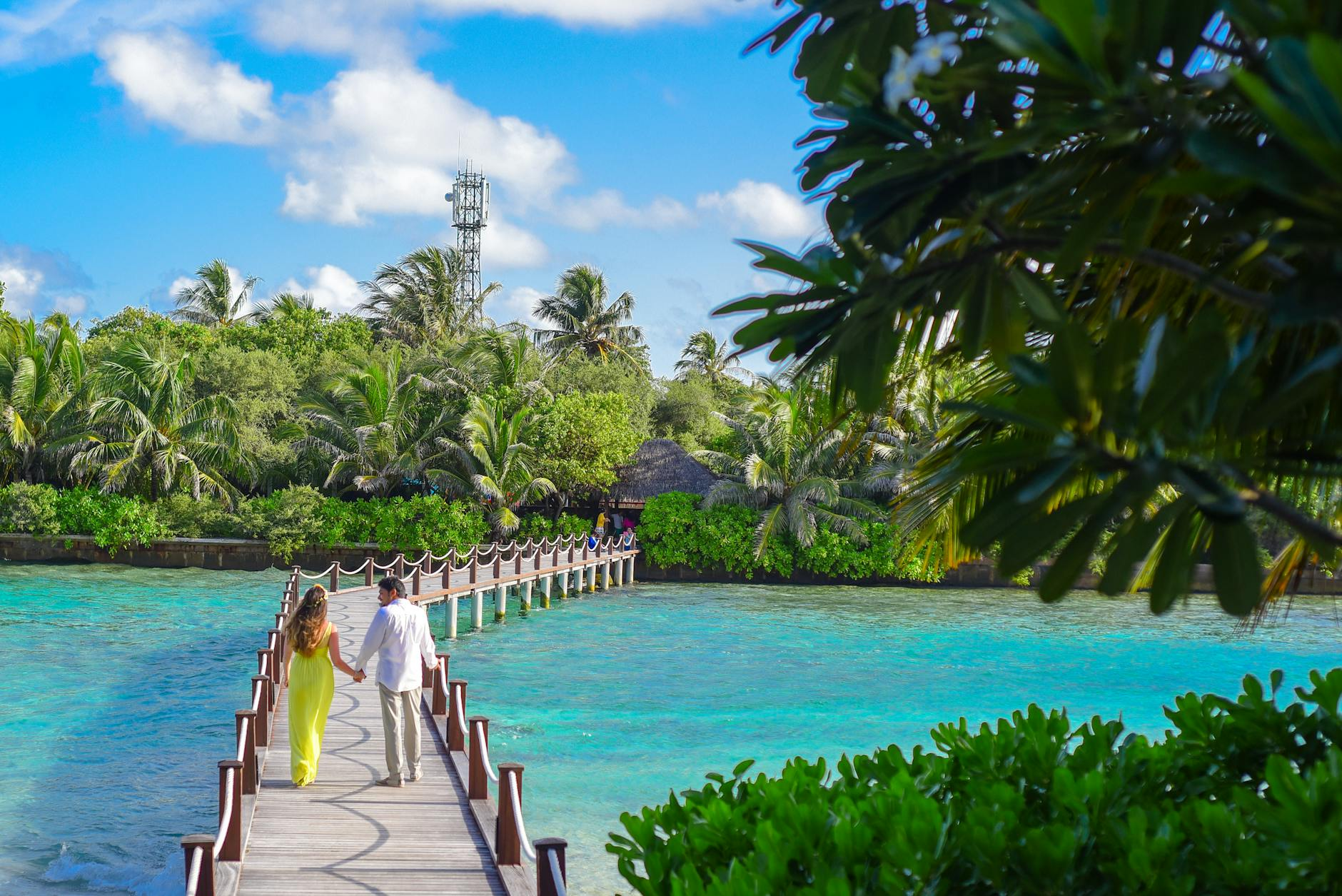 Couple holding hands on boardwalk in Caribbean paradise with crystal turquoise water