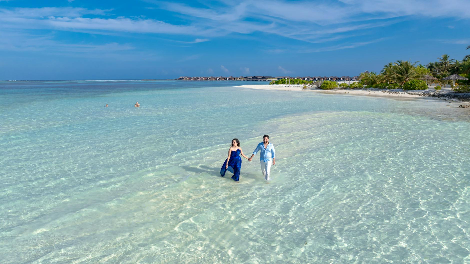Romantic couple walking along crystal clear turquoise water beach in paradise Maldives
