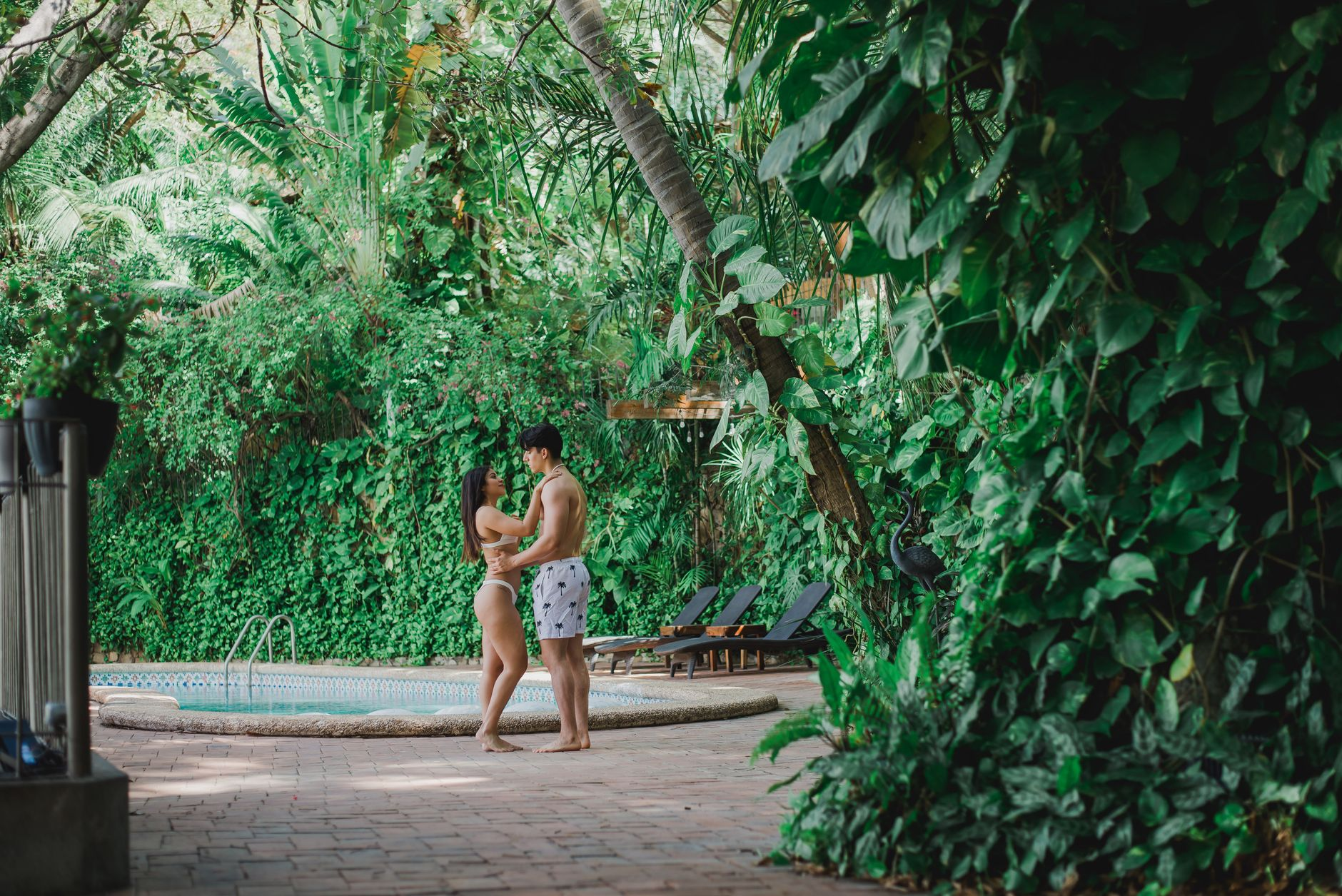 Couple in swimwear enjoying lush tropical poolside area at Mexico resort for romantic getaway